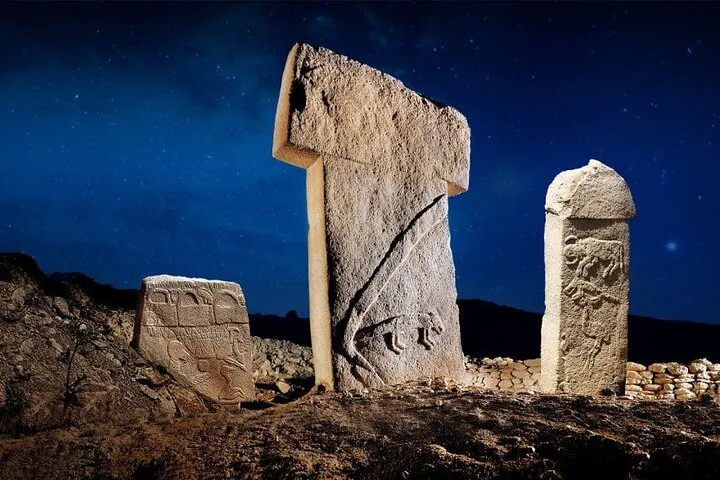 Carved T-shaped pillars lit at night under a starry sky on a Gobekli Tepe tour from Şanlıurfa, Turkey